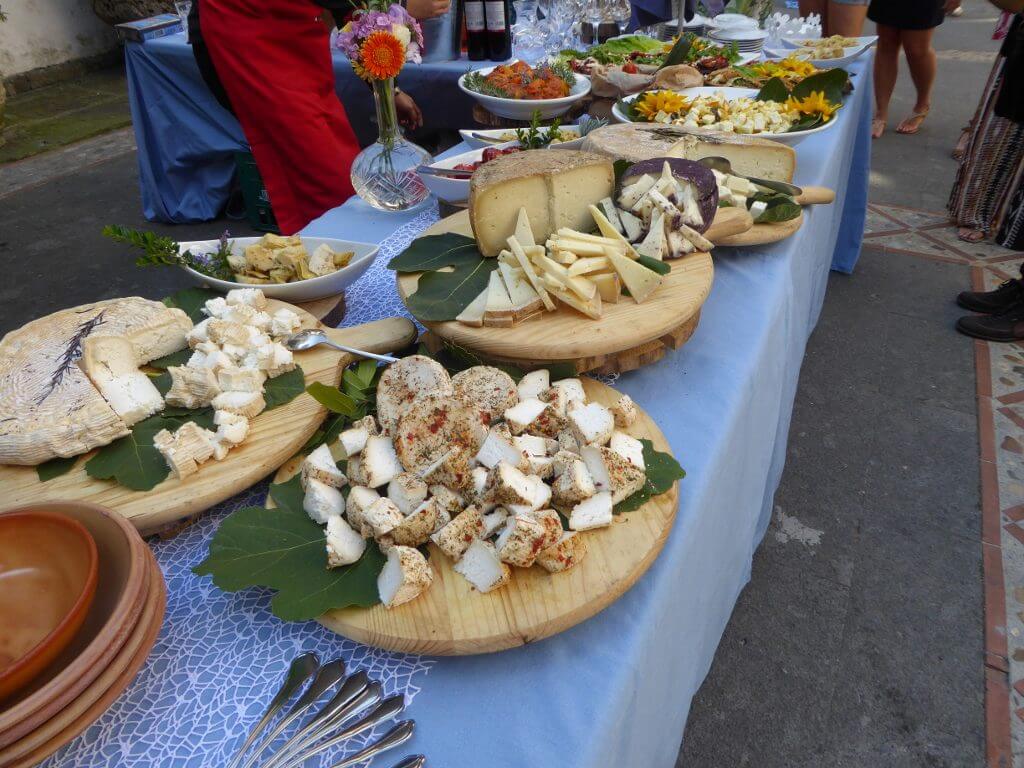 Long table with boards of cuts of different cheeses