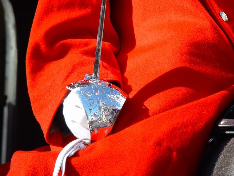 White gloved hand and silver sword against red coat of household cavalry guard