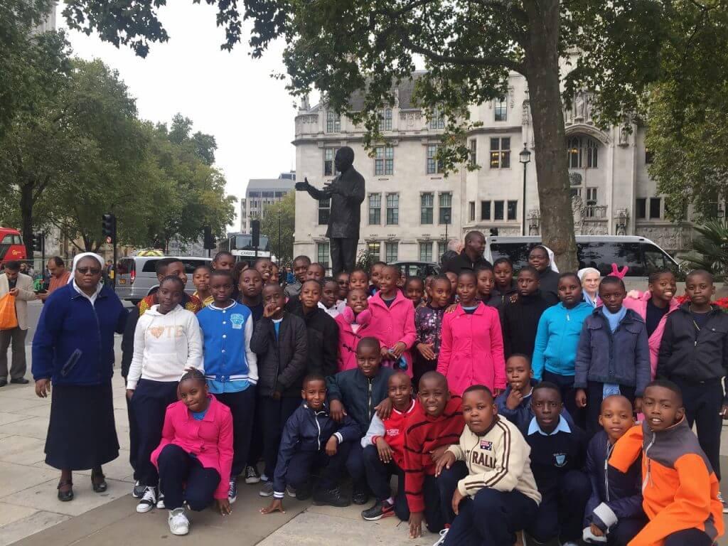 Group of African school children in front of statue of Nelson Mandela in Parliament Square