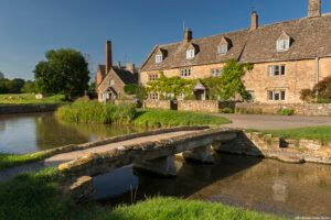 Traditional Cotswold stone cottages and stone footbridge in the Cotswolds village of Lower Slaughter.
