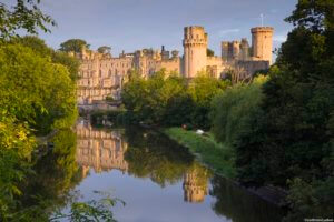 View of Warwick Castle, a medieval castle, from the River Avon. Grand imposing castle with medieval and Victorian buildings. River Avon.