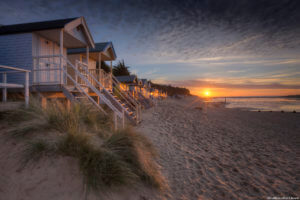 Sunset at high tide behind the old beach huts at Wells-next-the-sea on the North Norfolk coast.